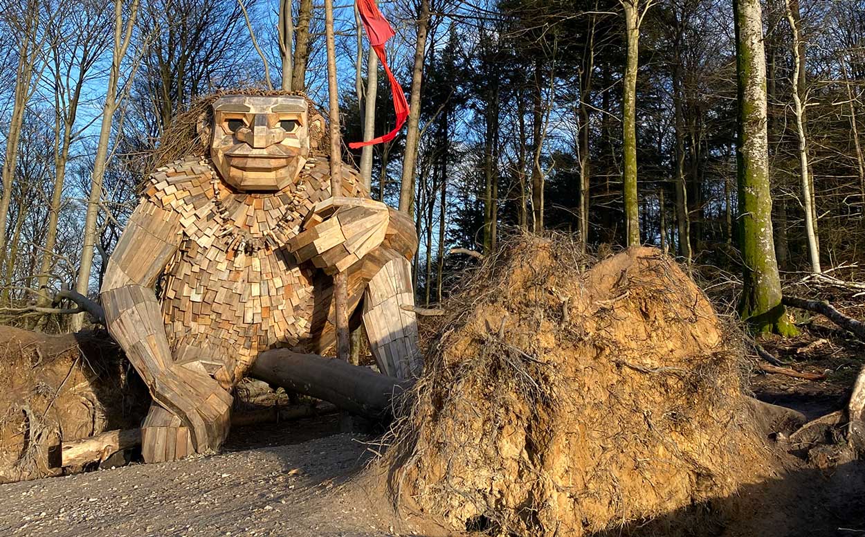 Trold af genbrugstræ sidder i skov med flag